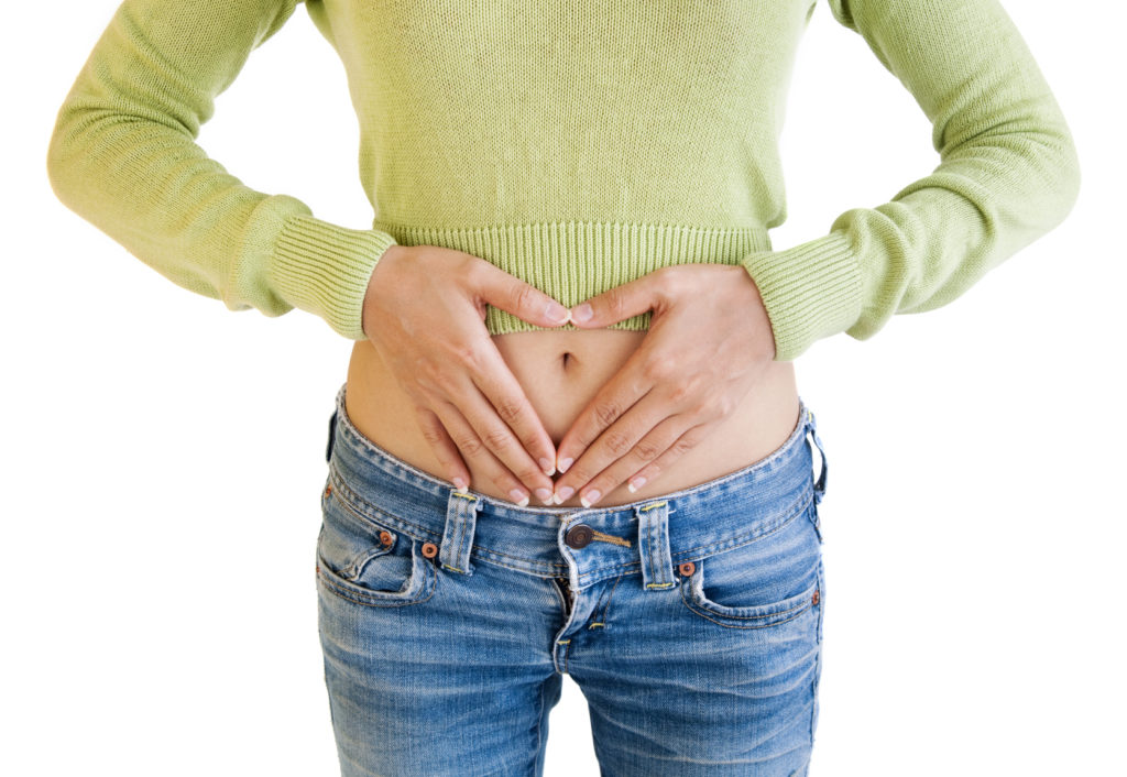 A woman's hands forming a heart symbol on belly